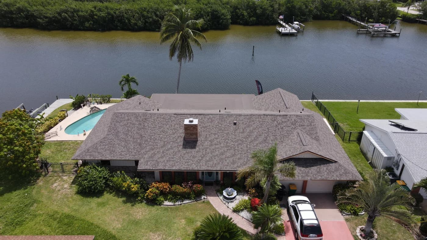 Aerial view of a waterfront Treasure Coast home with a clean asphalt shingle roof